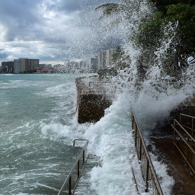 Large waves crash into the sidewalk in Waikiki