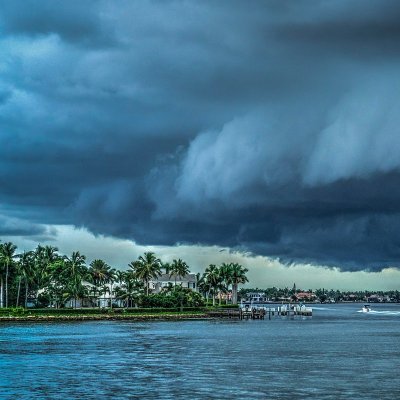 Large, dark storm clouds roll in over a residential bay