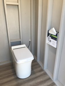 A toilet sits in a bare outdoor room.