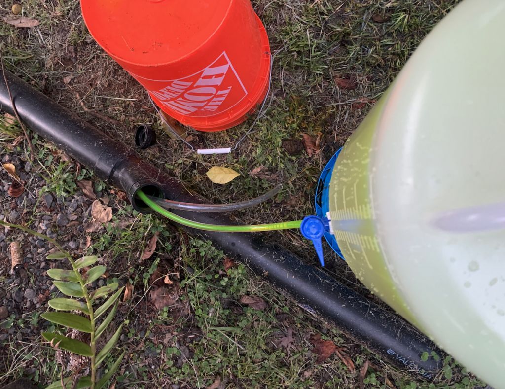 Siting down a container with green dye with tubes leading to a pipe