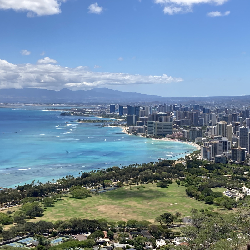 Scenic view looking down across the coastline and buildings of Waikiki, with the Waiʻanae Mountains in the background