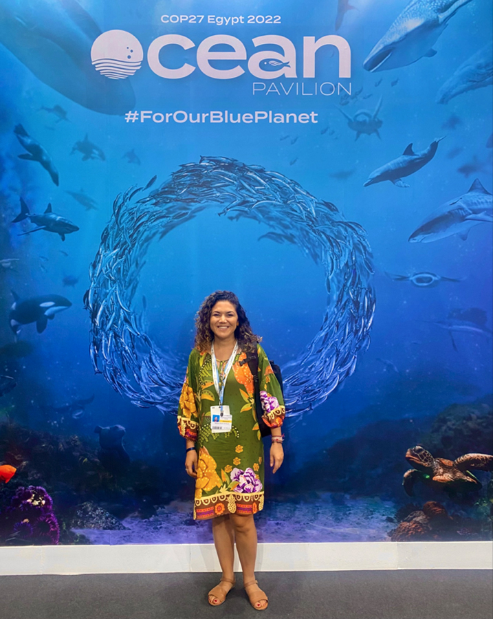 Author poses in front of a banner showing an underwater scene of ocean life.