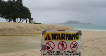 A sign warning against swimming and fishing due to sewage contaminated water on a closed beach