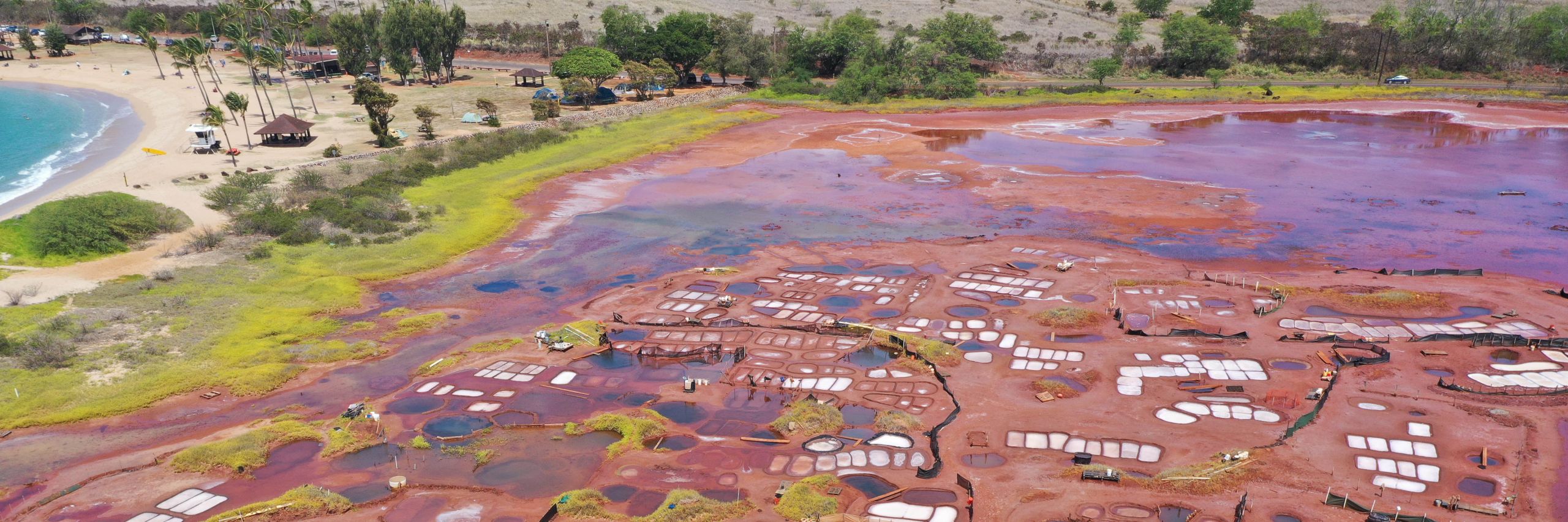 Aerial view of coastal salt ponds surrounded by red soil