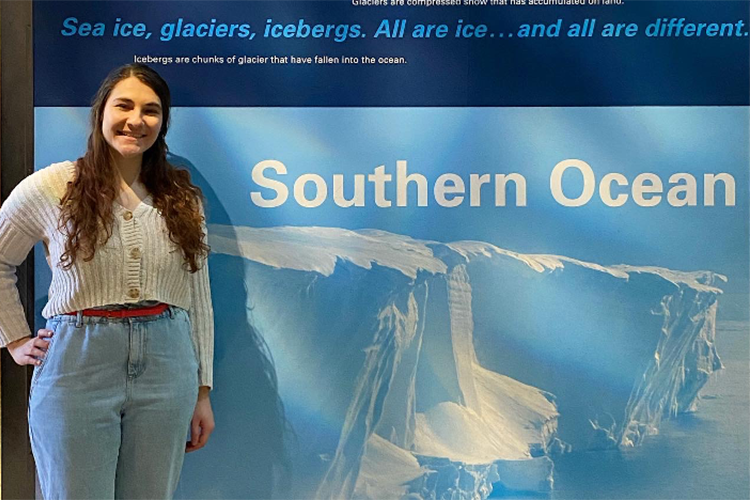 Fellow poses by wall poster of a glacier in the Southern Ocean