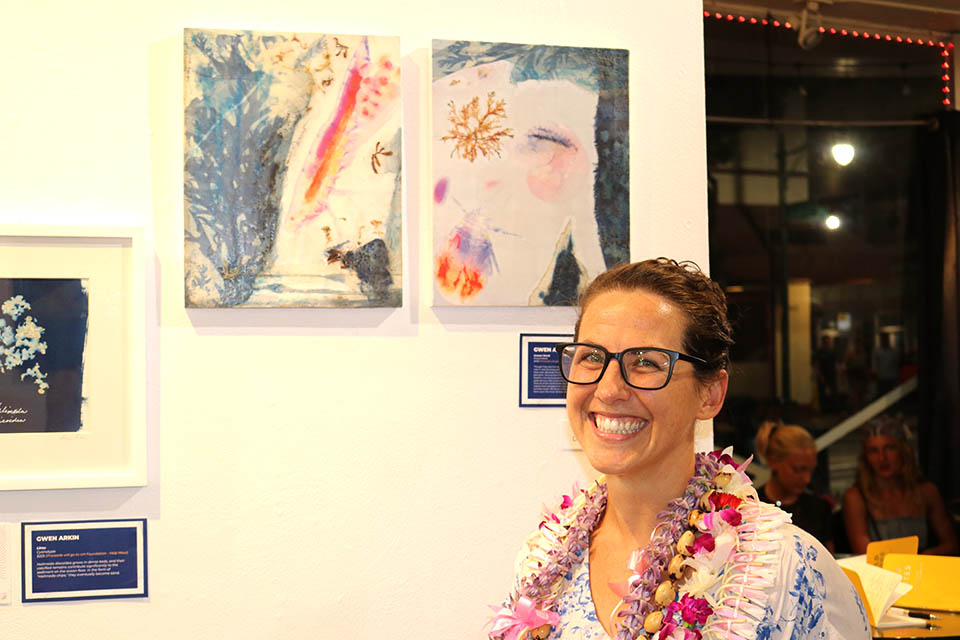 Beth Lenz posing in front of artwork in gallery.