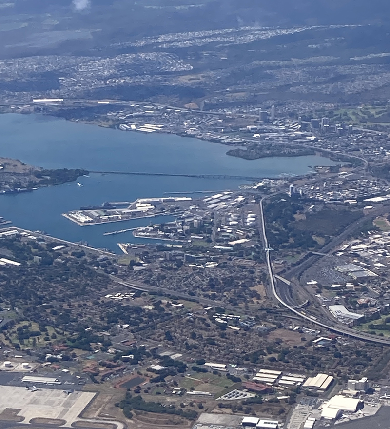 Aerial view looking north across the industrial, commercial, and residential development around the blue waters of Pearl Harbor